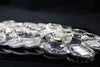 A pile of Canadian and international silver coins spilled across a black glass table