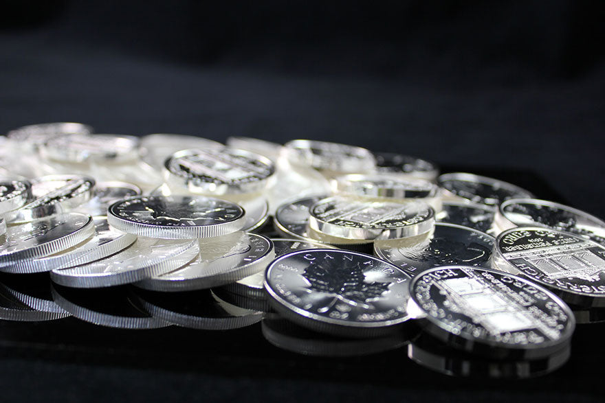 A pile of Canadian and international silver coins spilled across a black glass table